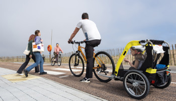 A cyclist towing a child in an attached child trailer