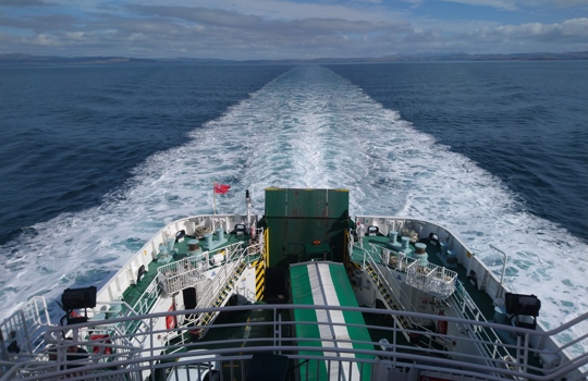 The view from the rear deck of a ferry on the move.